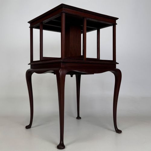 fig 5. A dark mahogany revolving bookcase featuring a two-tier rotating upper section supported by slender cabriole legs ending in pad feet.