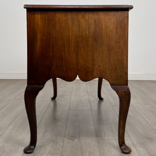 fig 6. A 19th-century Victorian writing table crafted from burr walnut with five drawer fronts, ornate brass drop handles, a shaped central kneehole, and cabriole legs.