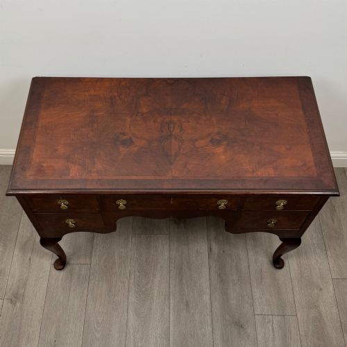 fig 8. A 19th-century Victorian writing table crafted from burr walnut with five drawer fronts, ornate brass drop handles, a shaped central kneehole, and cabriole legs.