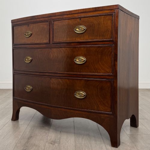 fig 1. An 18th-century Georgian mahogany bow-front chest of drawers featuring two short over two long drawers with brass oval handles and splayed bracket feet.