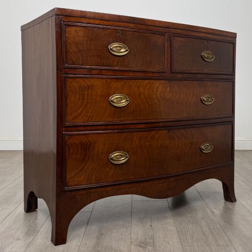 fig 7. An 18th-century Georgian mahogany bow-front chest of drawers featuring two short over two long drawers with brass oval handles and splayed bracket feet.