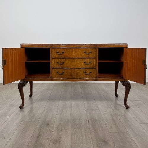 fig 1. An Edwardian burr walnut sideboard featuring three central drawers flanked by two cupboard doors, set on carved cabriole legs.