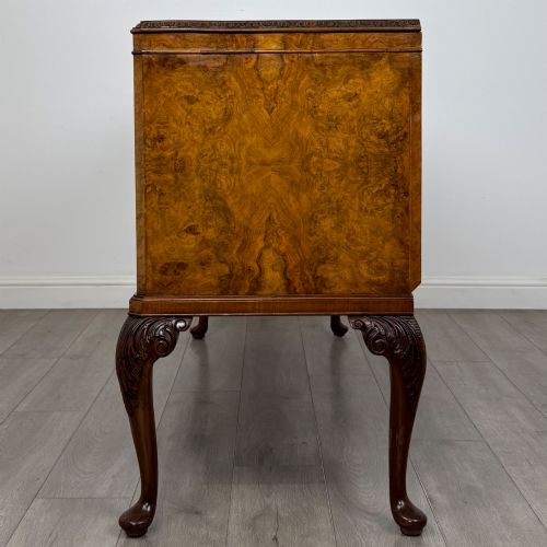fig 3. An Edwardian burr walnut sideboard featuring three central drawers flanked by two cupboard doors, set on carved cabriole legs.