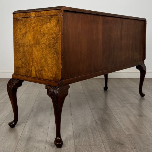 fig 4. An Edwardian burr walnut sideboard featuring three central drawers flanked by two cupboard doors, set on carved cabriole legs.
