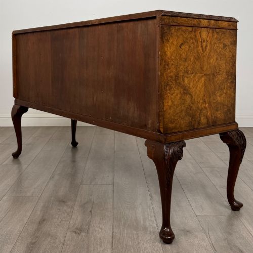fig 6. An Edwardian burr walnut sideboard featuring three central drawers flanked by two cupboard doors, set on carved cabriole legs.