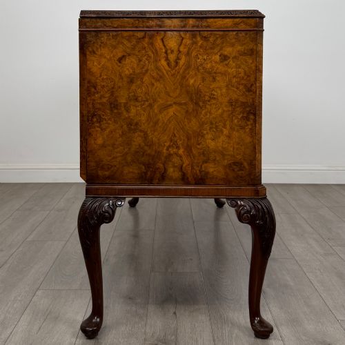 fig 7. An Edwardian burr walnut sideboard featuring three central drawers flanked by two cupboard doors, set on carved cabriole legs.