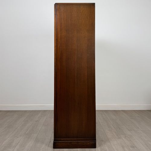 fig 3. A freestanding mid-20th-century double wardrobe crafted from medium brown oak with twin flush doors, small circular wooden handles, and a low plinth base.