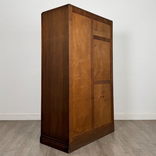 fig 4. A freestanding mid-20th-century double wardrobe crafted from medium brown oak with twin flush doors, small circular wooden handles, and a low plinth base.