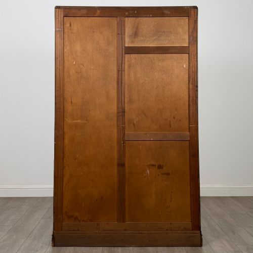 fig 5. A freestanding mid-20th-century double wardrobe crafted from medium brown oak with twin flush doors, small circular wooden handles, and a low plinth base.