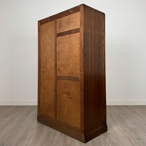 fig 6. A freestanding mid-20th-century double wardrobe crafted from medium brown oak with twin flush doors, small circular wooden handles, and a low plinth base.