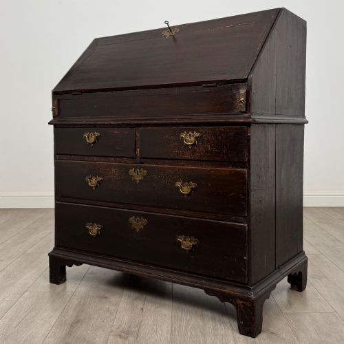 fig 2. An 18th-century dark oak Georgian bureau with a slant-front writing slope, brass batwing drop handles, and bracket feet.