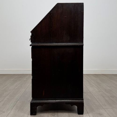 fig 3. An 18th-century dark oak Georgian bureau with a slant-front writing slope, brass batwing drop handles, and bracket feet.