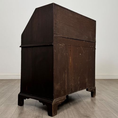 fig 4. An 18th-century dark oak Georgian bureau with a slant-front writing slope, brass batwing drop handles, and bracket feet.