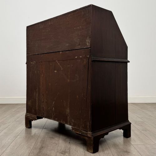 fig 6. An 18th-century dark oak Georgian bureau with a slant-front writing slope, brass batwing drop handles, and bracket feet.