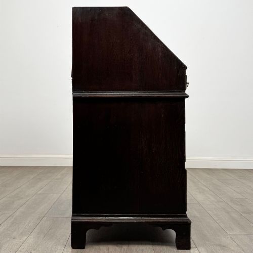 fig 7. An 18th-century dark oak Georgian bureau with a slant-front writing slope, brass batwing drop handles, and bracket feet.