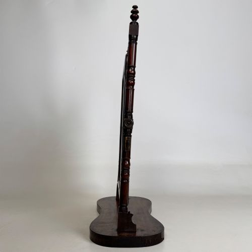 fig 3. A 19th-century mahogany dressing mirror with turned side columns, carved scrollwork cresting, and an adjustable rectangular glass frame on a shaped base.