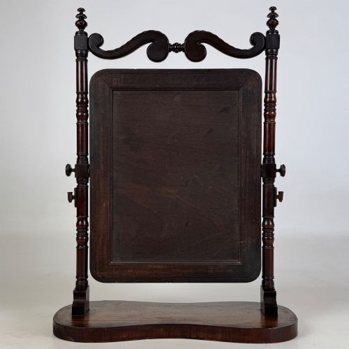 fig 6. A 19th-century mahogany dressing mirror with turned side columns, carved scrollwork cresting, and an adjustable rectangular glass frame on a shaped base.