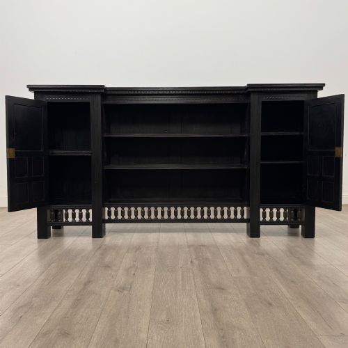 fig 2. An antique ebonised black wood sideboard featuring a central open bookshelf, two carved side doors with glass panels, brass hardware, and a spindled lower rail.