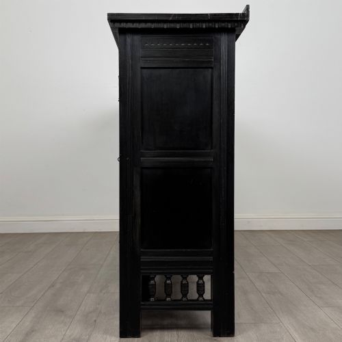 fig 4. An antique ebonised black wood sideboard featuring a central open bookshelf, two carved side doors with glass panels, brass hardware, and a spindled lower rail.