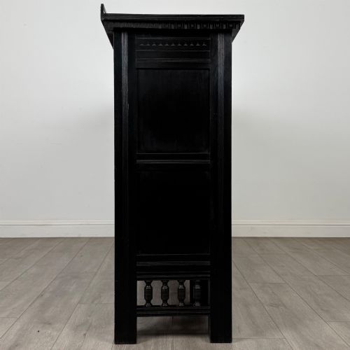 fig 8. An antique ebonised black wood sideboard featuring a central open bookshelf, two carved side doors with glass panels, brass hardware, and a spindled lower rail.