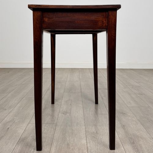 fig 2. An antique dark oak Edwardian side table with two front drawers, metallic drop handles, and straight tapered legs.