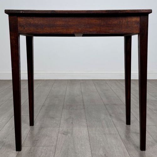 fig 4. An antique dark oak Edwardian side table with two front drawers, metallic drop handles, and straight tapered legs.
