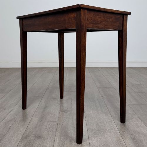 fig 5. An antique dark oak Edwardian side table with two front drawers, metallic drop handles, and straight tapered legs.
