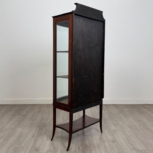 fig 4. An Edwardian mahogany display cabinet with a bow-front glazed door, fabric-lined interior shelves, marquetry inlay, and slender tapered legs with a lower shelf.