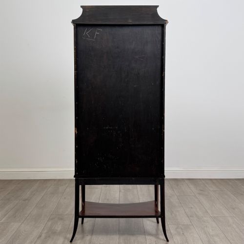 fig 5. An Edwardian mahogany display cabinet with a bow-front glazed door, fabric-lined interior shelves, marquetry inlay, and slender tapered legs with a lower shelf.
