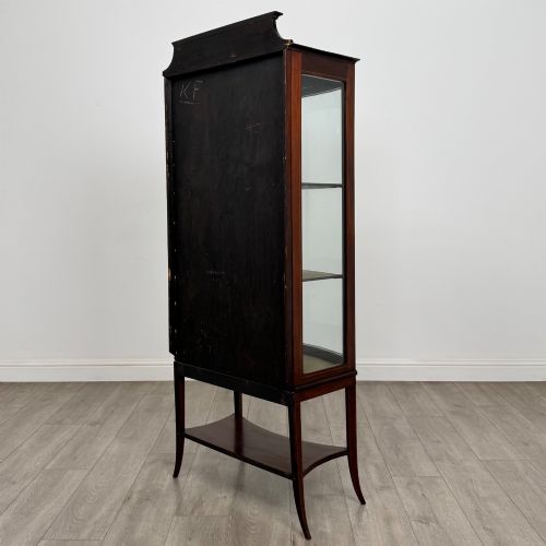 fig 6. An Edwardian mahogany display cabinet with a bow-front glazed door, fabric-lined interior shelves, marquetry inlay, and slender tapered legs with a lower shelf.