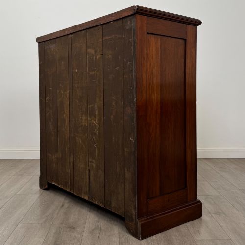 fig 5. An Edwardian walnut chest of drawers featuring a two over three drawer layout with brass drop handles and a solid plinth base.