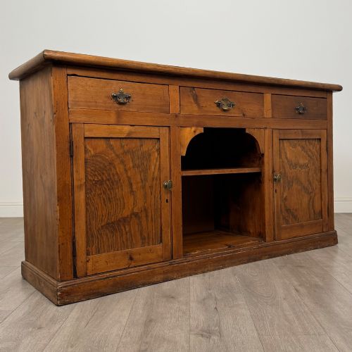fig 8. A 19th-century pine farmhouse dresser base featuring three upper drawers above two cupboard doors and an open central shelf.