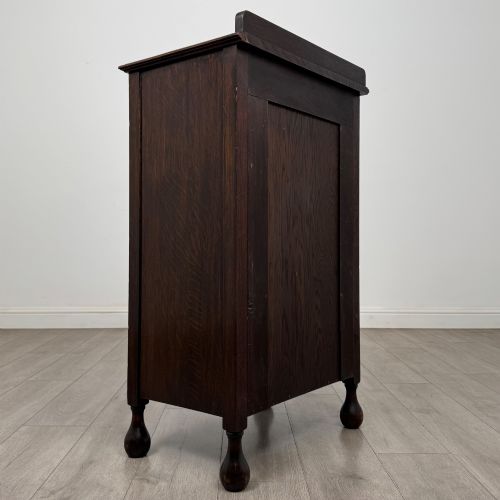 fig 4. An Edwardian dark brown oak display cabinet featuring a single glazed door and turned feet.