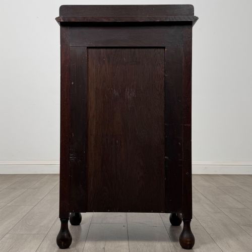 fig 5. An Edwardian dark brown oak display cabinet featuring a single glazed door and turned feet.