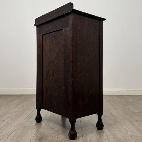 fig 6. An Edwardian dark brown oak display cabinet featuring a single glazed door and turned feet.