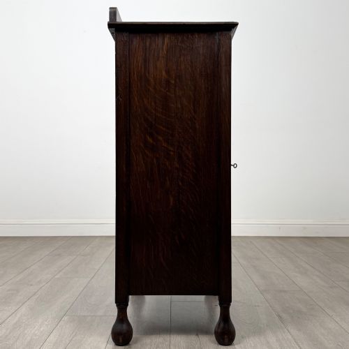 fig 7. An Edwardian dark brown oak display cabinet featuring a single glazed door and turned feet.