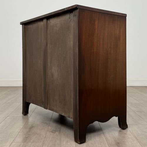 fig 5. A mahogany serpentine chest of drawers featuring four graduating drawer tiers with brass handles and a curved front profile.