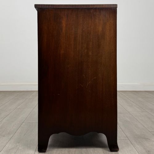 fig 6. A mahogany serpentine chest of drawers featuring four graduating drawer tiers with brass handles and a curved front profile.