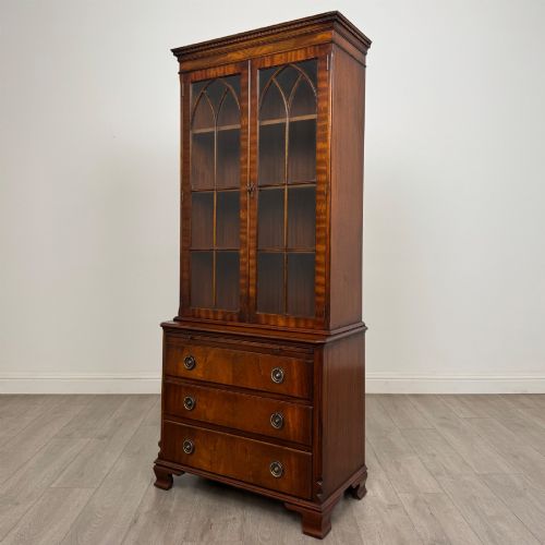 fig 3. A tall Georgian style mahogany bookcase featuring two glazed doors with gothic arch tracery above a lower section with three drawers.