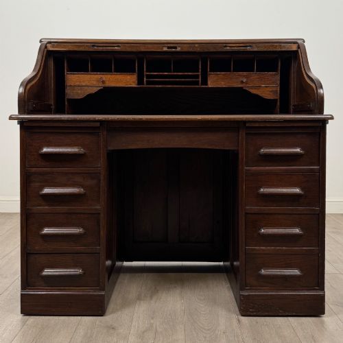 fig 1. An Edwardian dark oak roll top desk featuring a slatted tambour front above a twin pedestal base with eight drawers.