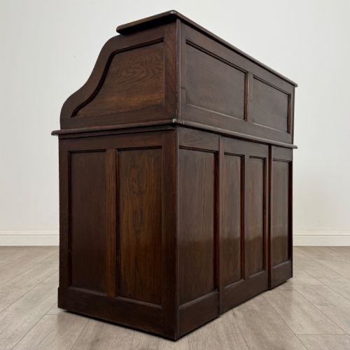 fig 4. An Edwardian dark oak roll top desk featuring a slatted tambour front above a twin pedestal base with eight drawers.