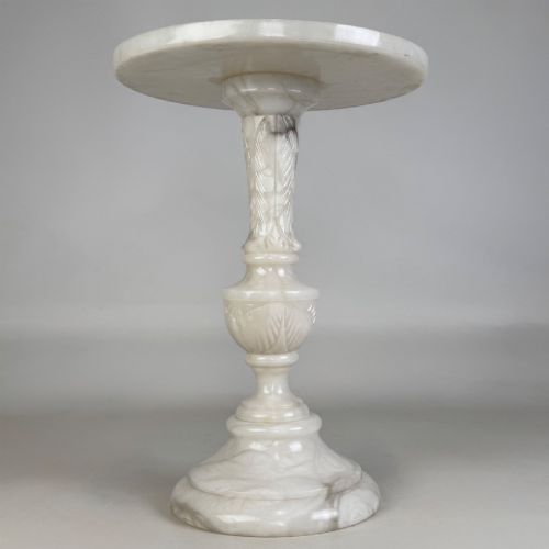 fig 2. A carved white alabaster side table featuring a circular top resting on a decorative turned pedestal stem and round base.
