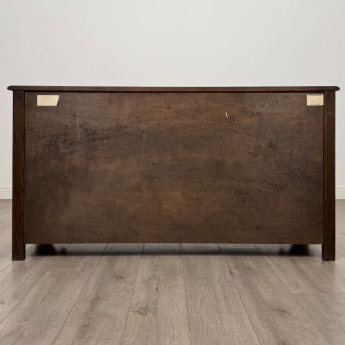 fig 5. A dark oak sideboard featuring carved linenfold central doors flanked by eight drawers with metal drop ring handles.