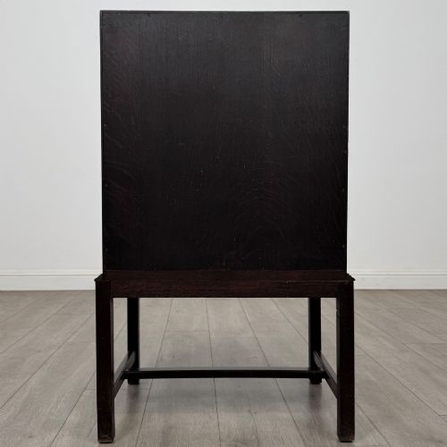fig 5. A small Edwardian dark oak writing bureau on a tall stand with two drawers featuring carved central panels and turned knobs.