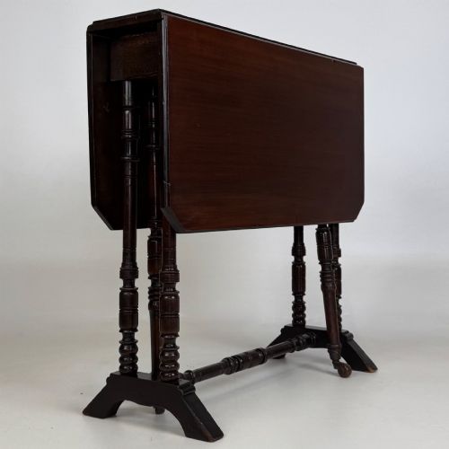 fig 5. A twentieth-century dark mahogany drop-leaf table featuring turned legs, a central stretcher rail, and folding side flaps.