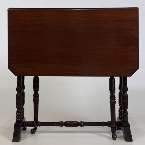 fig 6. A twentieth-century dark mahogany drop-leaf table featuring turned legs, a central stretcher rail, and folding side flaps.