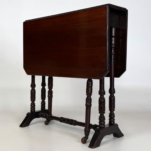 fig 7. A twentieth-century dark mahogany drop-leaf table featuring turned legs, a central stretcher rail, and folding side flaps.