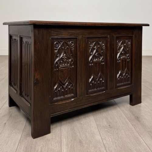 fig 7. A dark oak blanket box featuring three front panels decorated with detailed Gothic arch and shield carvings.