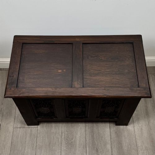 fig 8. A dark oak blanket box featuring three front panels decorated with detailed Gothic arch and shield carvings.