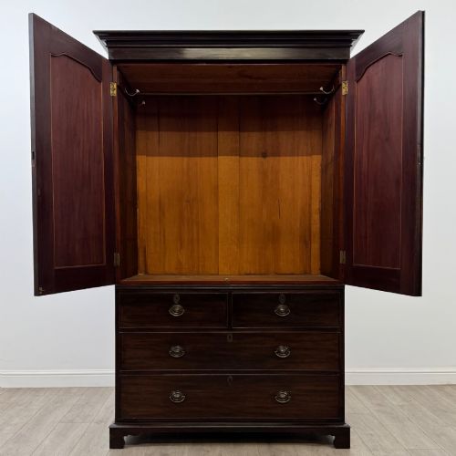 fig 1. A tall 19th-century dark mahogany linen press featuring carved panelled doors on top and a chest of four drawers at the base.
